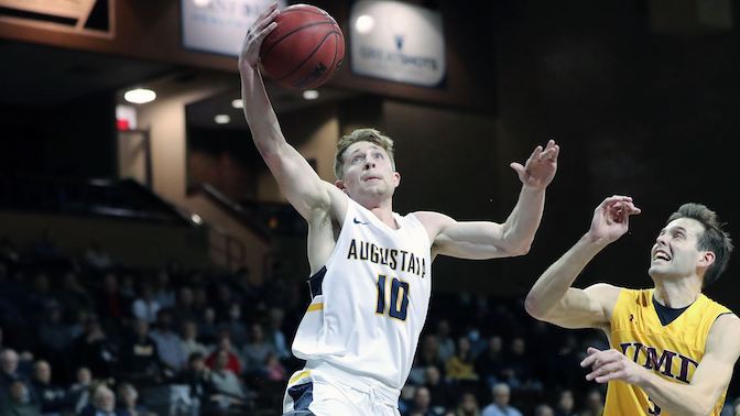 A basketball player reaches for a basketball while guarding himself from an opponent